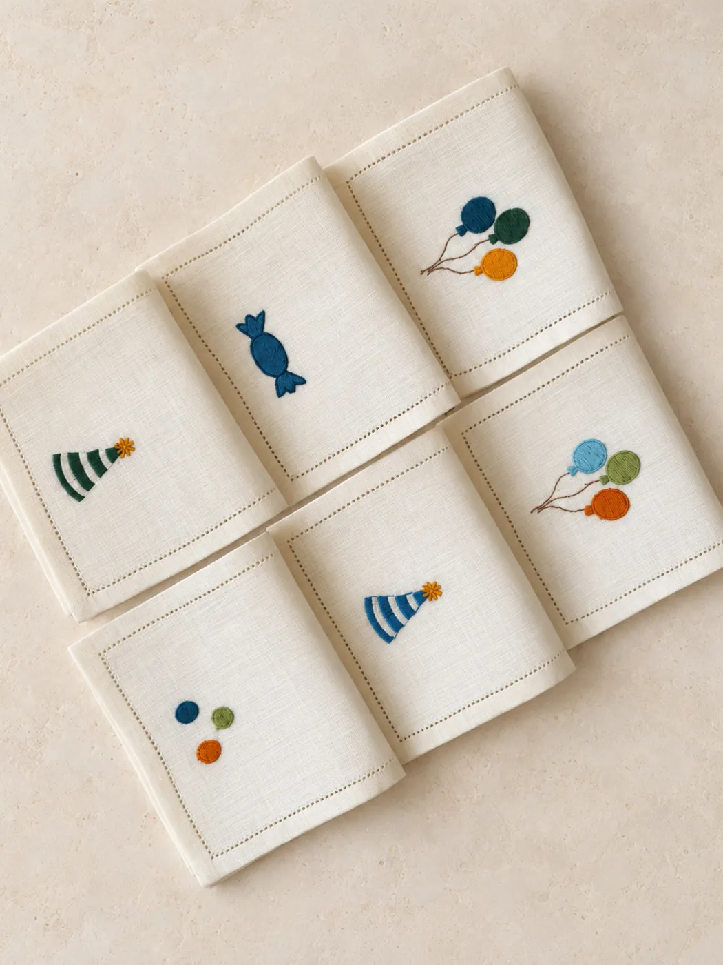Linen napkins embroidered with balloons, party hats and sweets