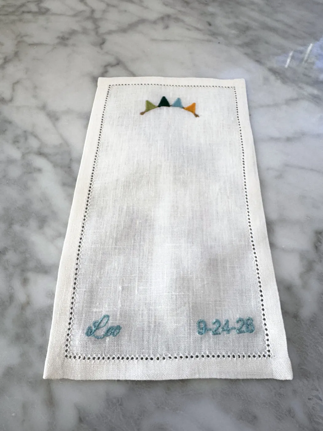 Linen napkin embroidered with bunting, a name and a date